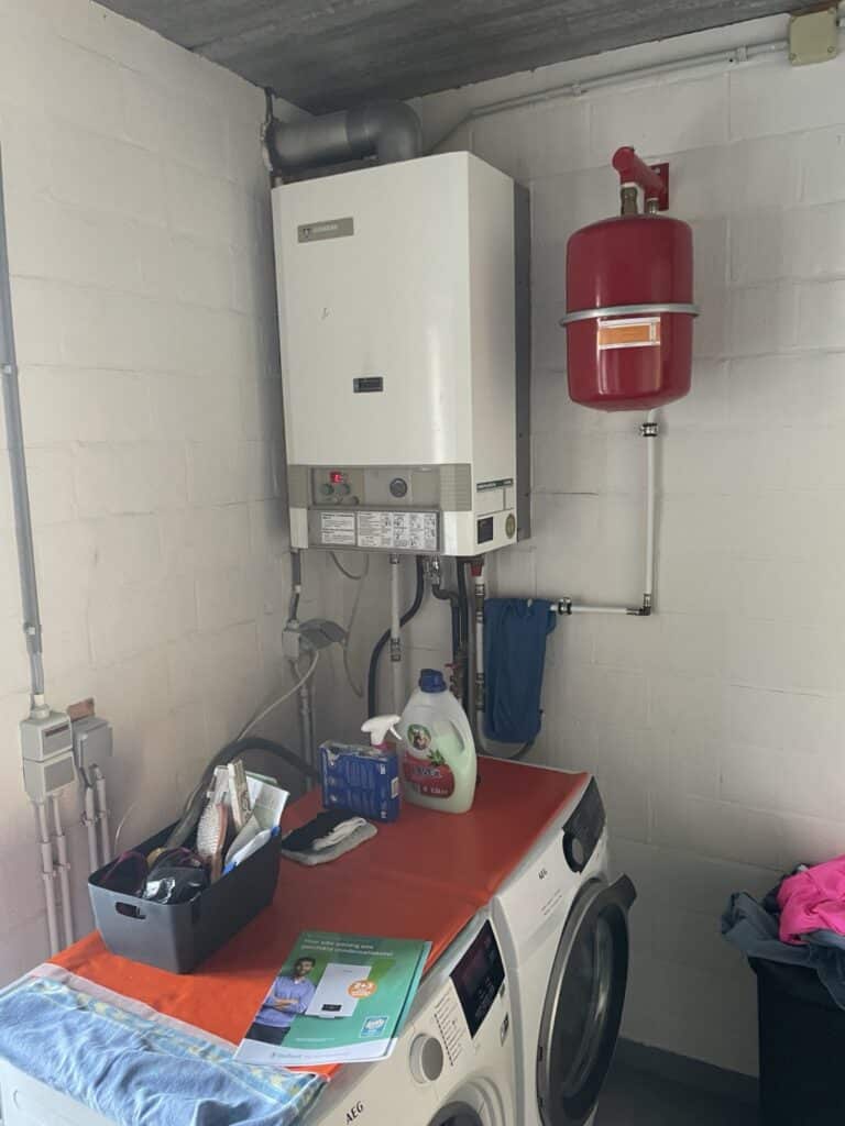 Oude Junkers gasketel met rood expansievat in een berging in Nieuwerkerken, voor de vervanging