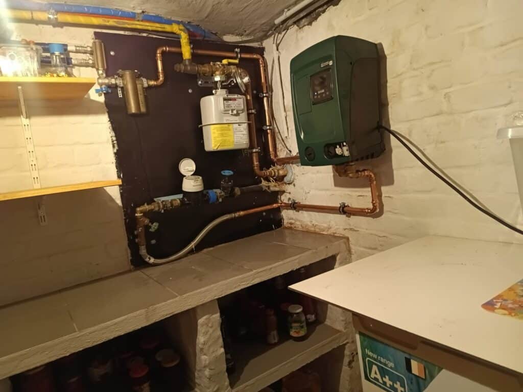 Watermeter met filter en de nieuwe drukverhogingspomp op de kelderwand in Mere